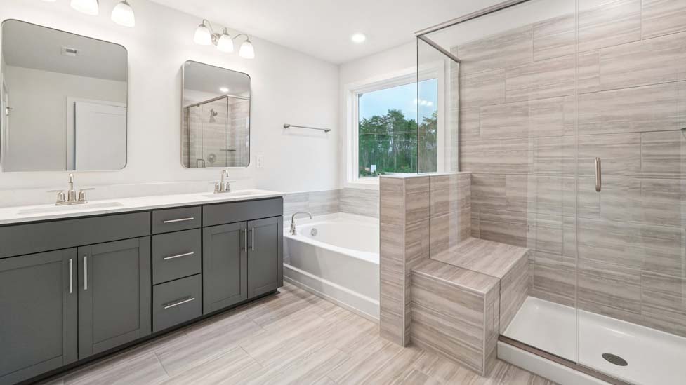 Primary bathroom with white cabinets and counters, view of closet