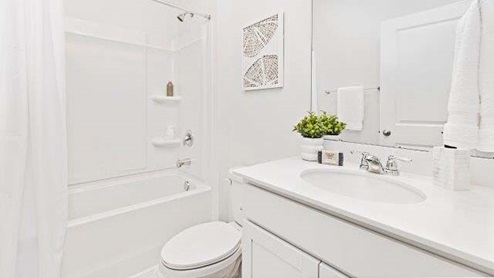 Bathroom with white cabinets and counter, and bathtub