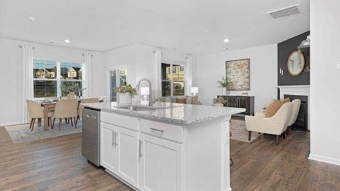 Kitchen and island with white cabinets, quarts countertops, wood floors, and stainless steel appliances