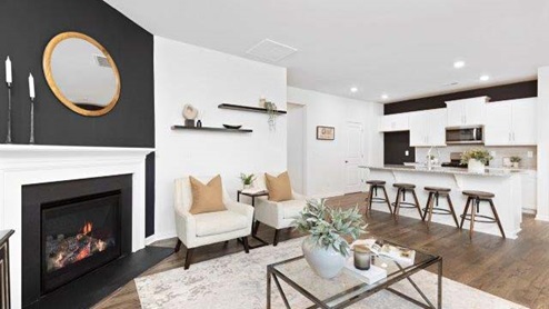 Modern open-concept living room with wood floors, and a fireplace, located beside kitchen