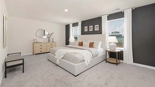 Carpeted primary bedroom with large windows
