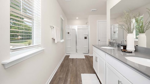 Primary bathroom with double sink vanity and standing glass door shower