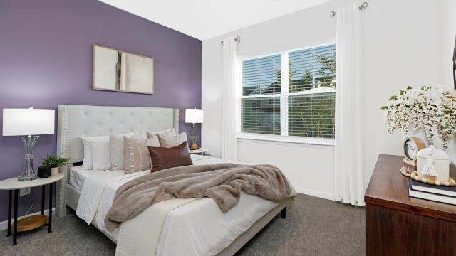 Carpeted bedroom with large window. New Home in Charlotte, North Carolina