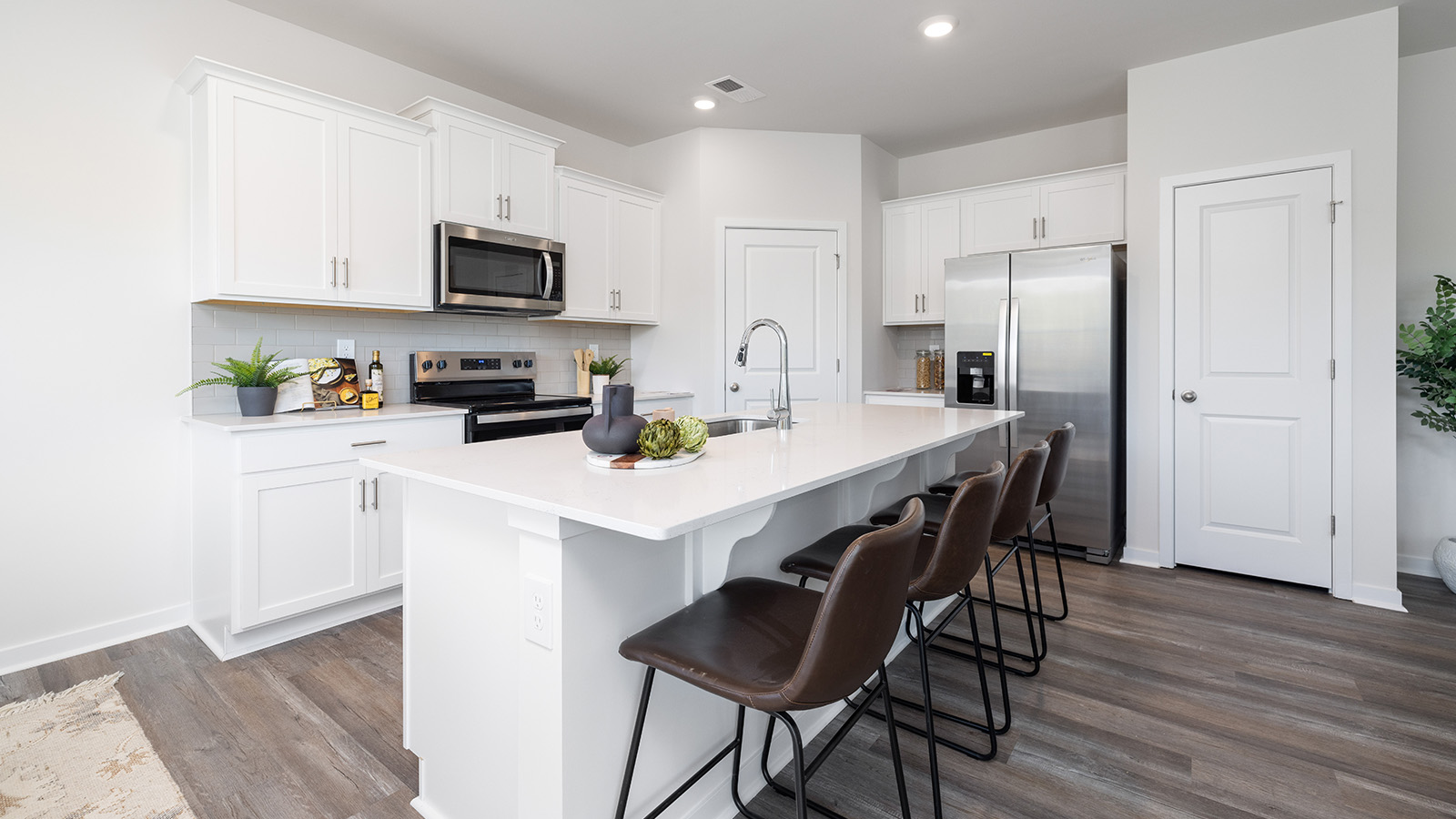 Open concept kitchen with large island bar and white cabinets and countertops and stainless steel appliances