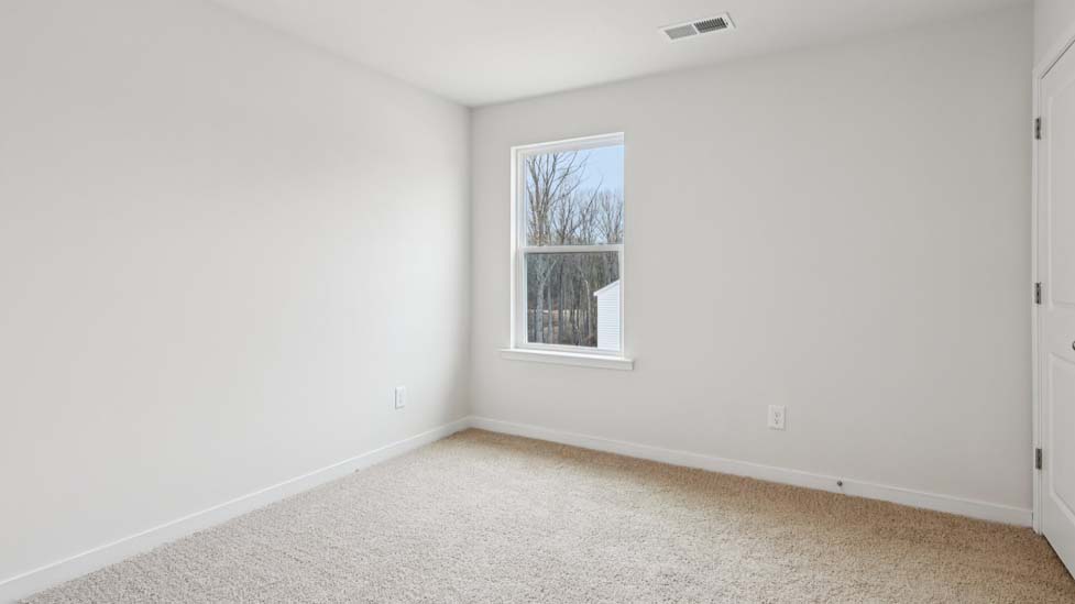 Carpeted bedroom with large window, view of bathroom door
