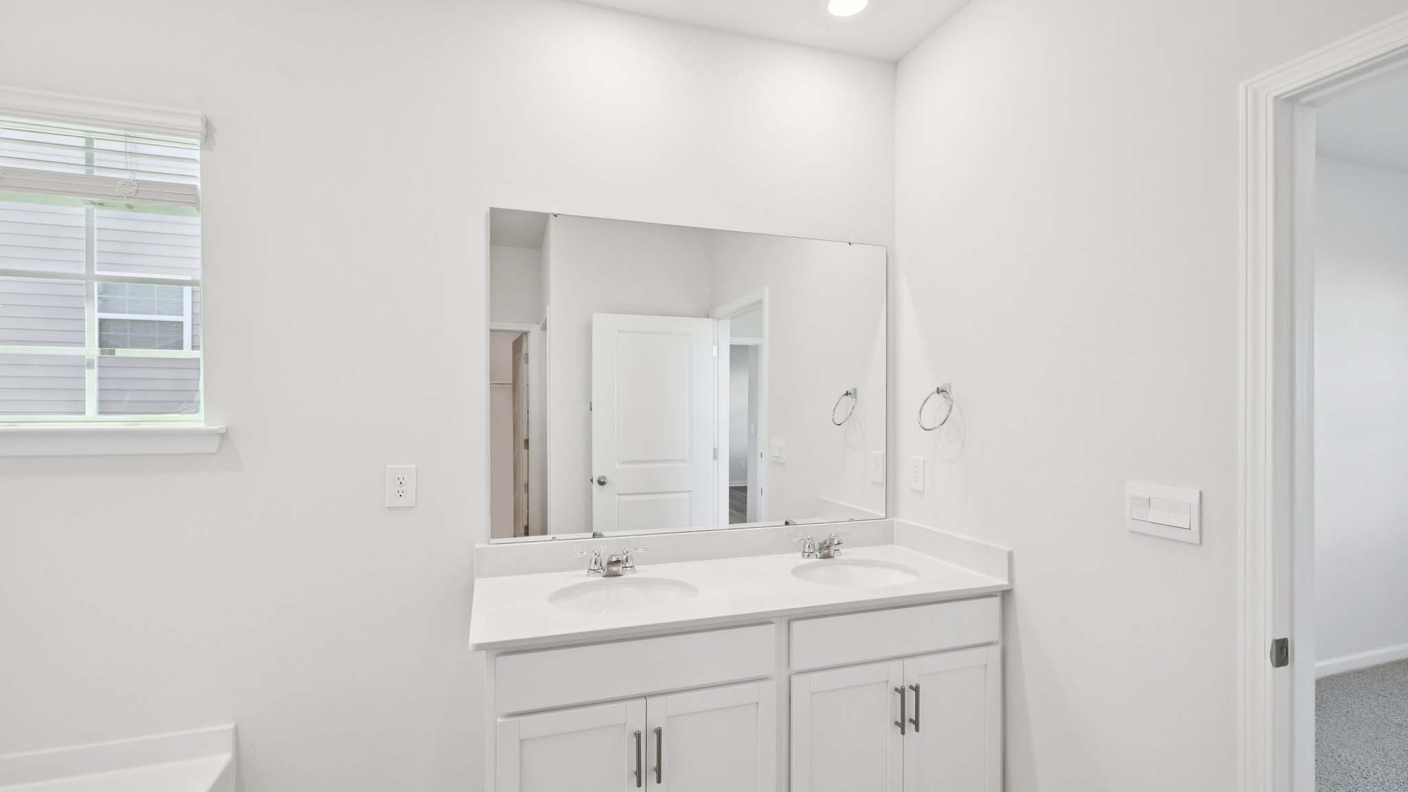 Bathroom with white cabinets and counters, and glass door shower