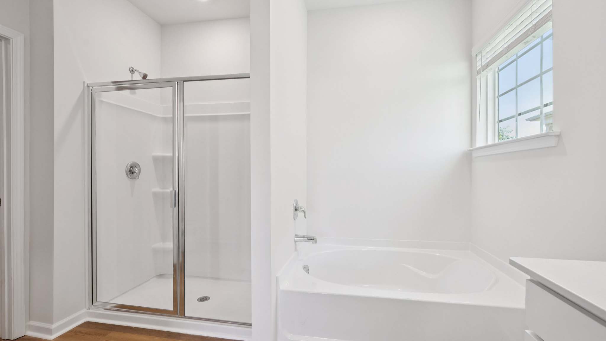 Bathroom with white cabinets and counters, and glass door shower
