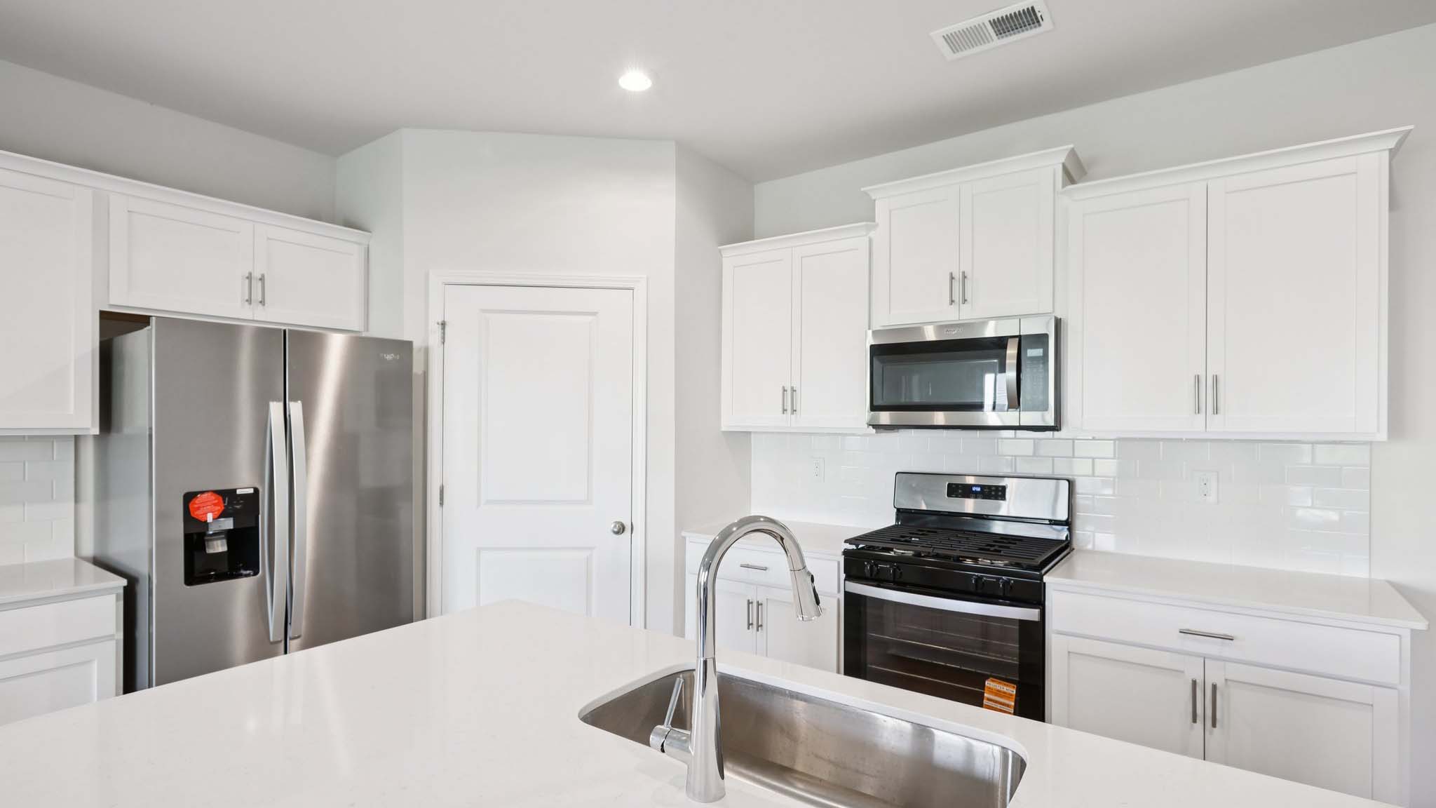 Kitchen and island with white cabinets and subway tiles and stainless steel subway tiles