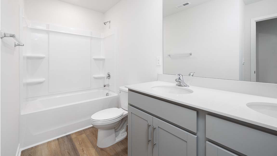 Bathroom with double sinks, white counters and cabinets, bathtub
