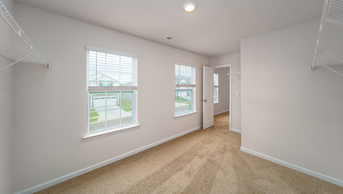 Primary bedroom walk in closet with two windows