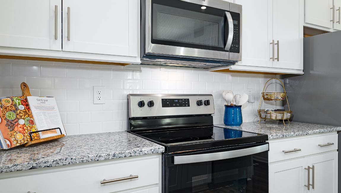 kitchen and island with white cabinets, wood floors and stainless steel appliances
