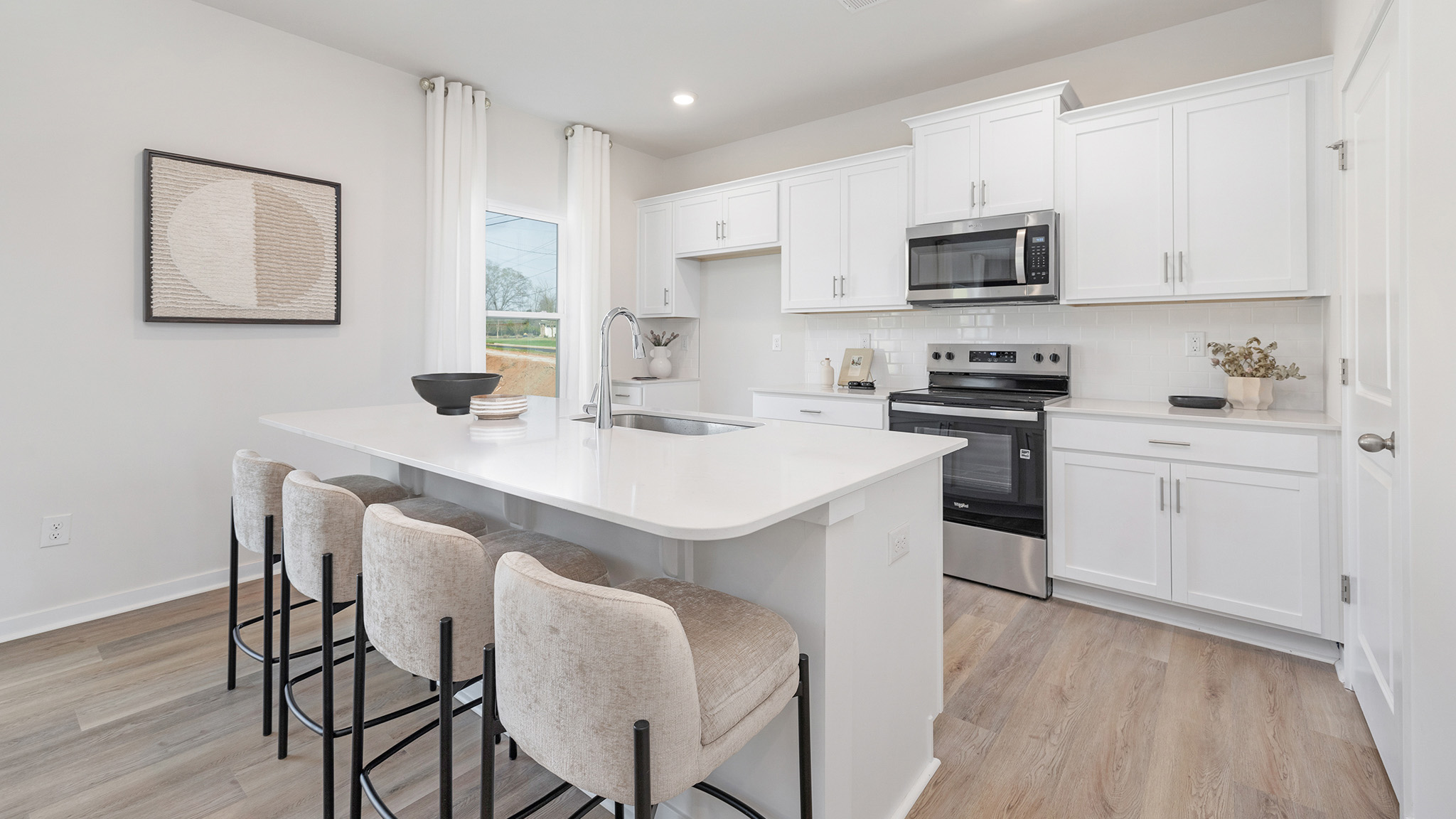 kitchen and island with white cabinets, wood floors and stainless steel appliances