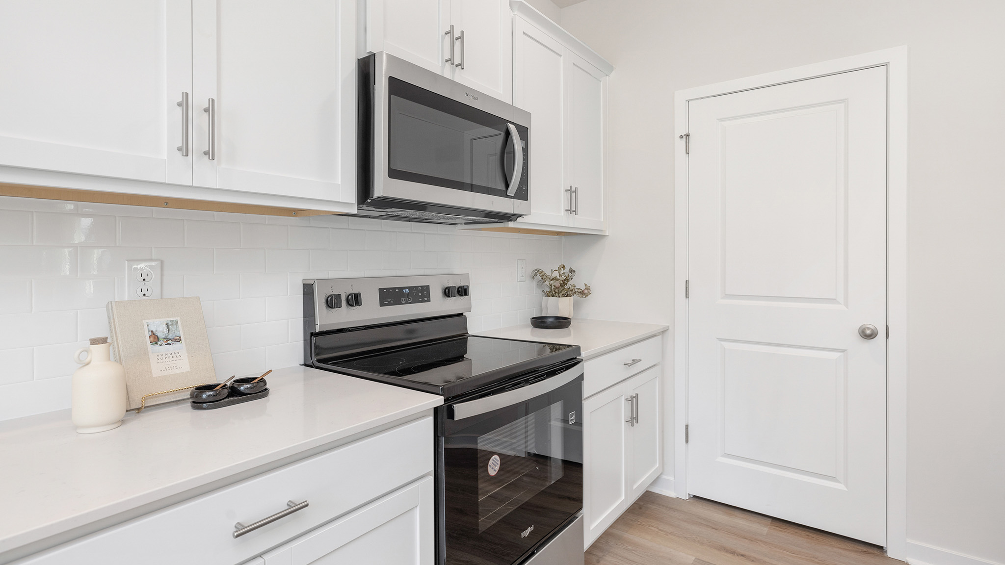 kitchen and island with white cabinets, wood floors and stainless steel appliances