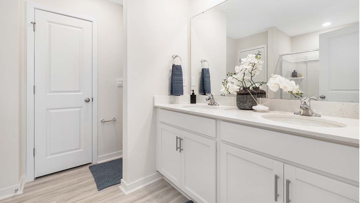 Primary bathroom with double sinks, white cabinets and counters