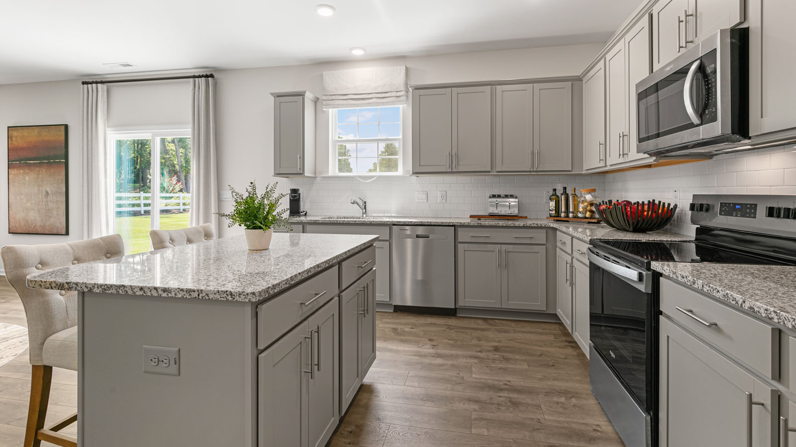 Kitchen with stainless steel appliances, revwood flooring, shaker style cabinets and and island