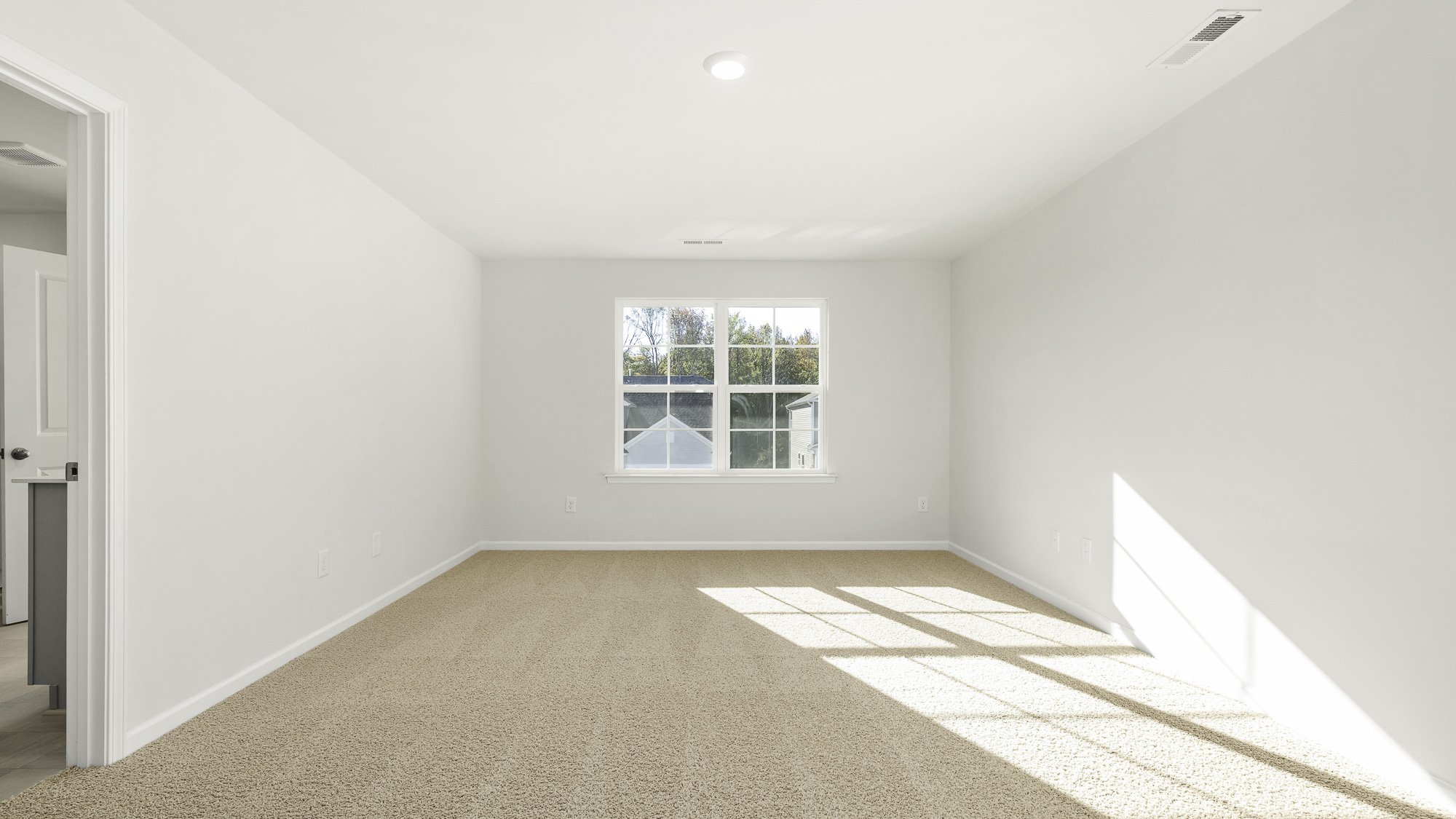 Interior room featuring neutral wall paint, wall-to-wall carpeting, and a multi-pane window