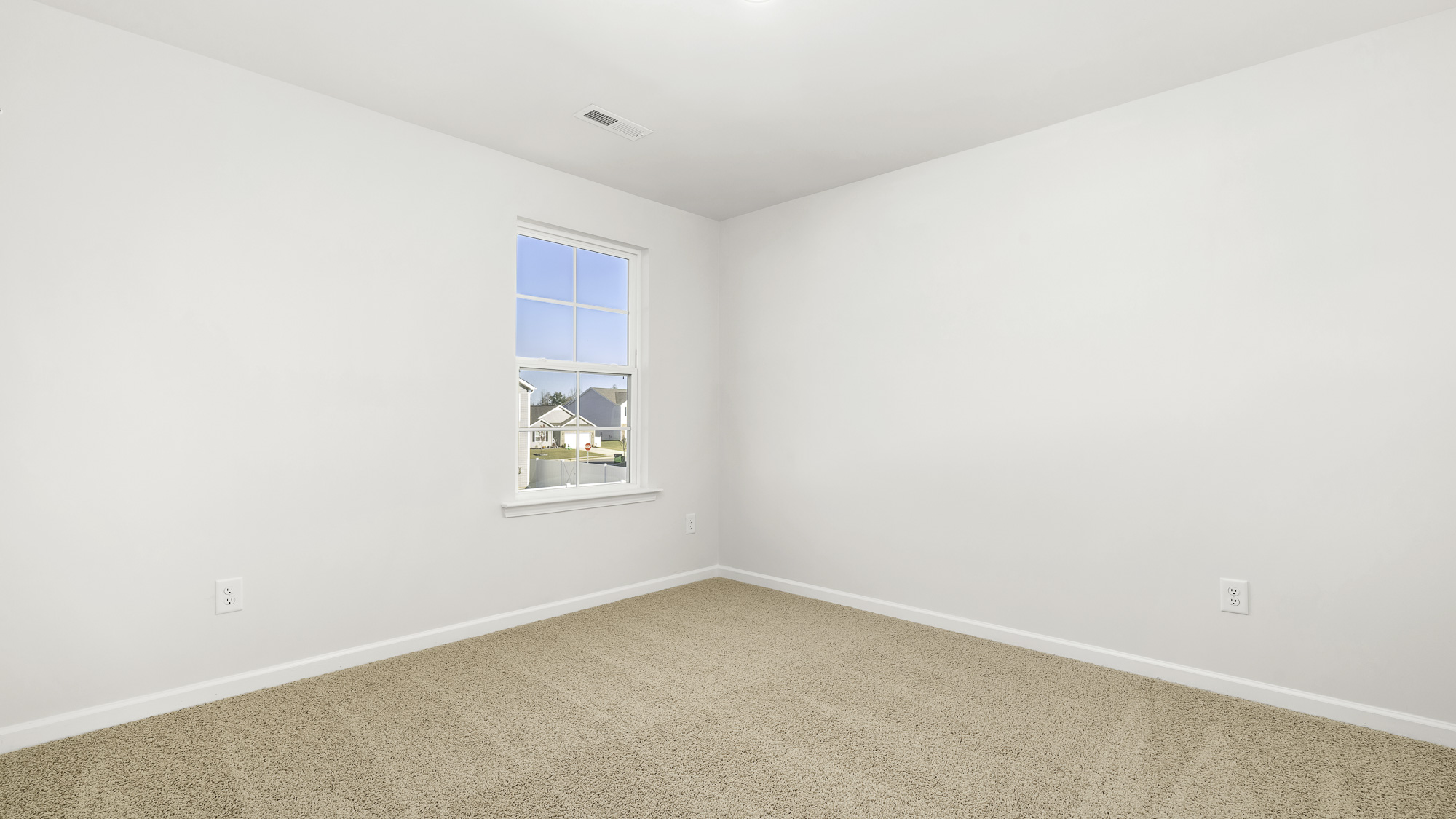 Neutral-toned interior space featuring light-colored wall paint, wall-to-wall carpeting, and a single-pane window with a grid pattern