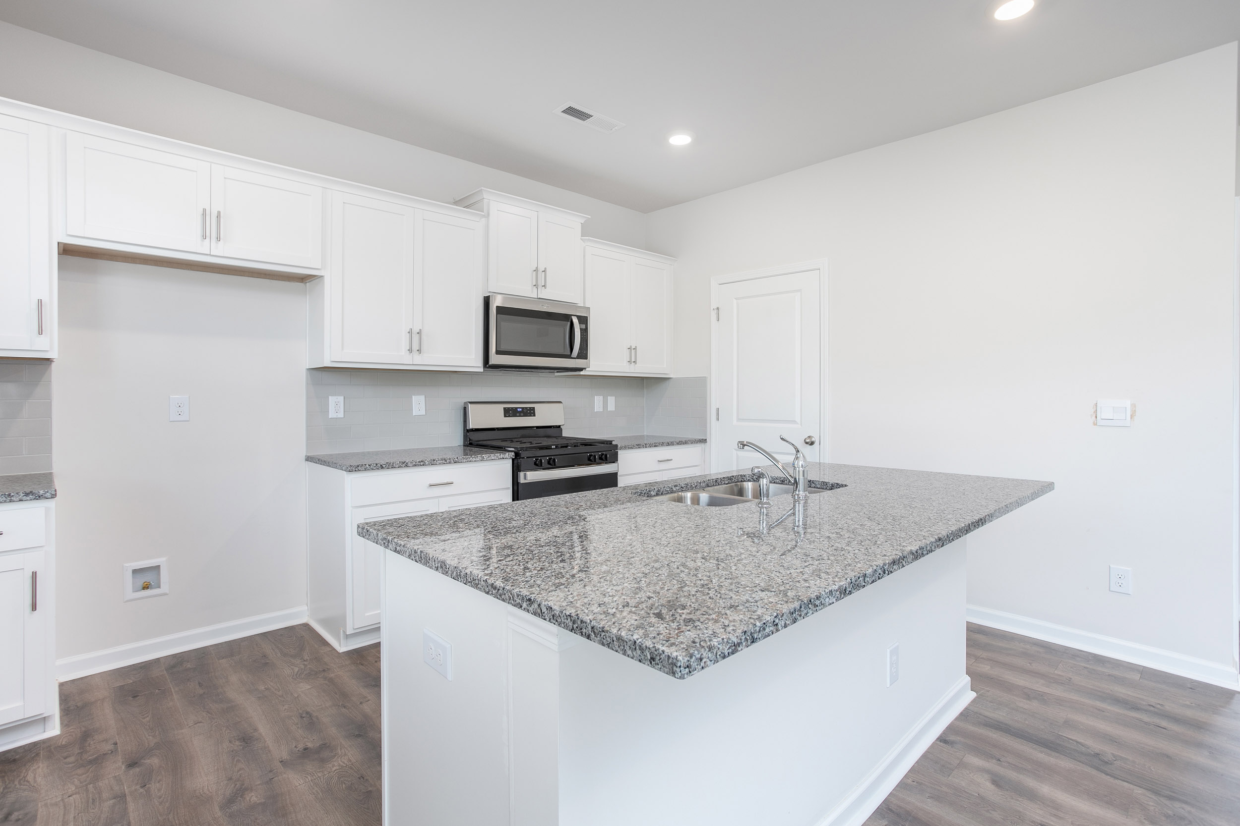 kitchen with island, revwood floors, and stainless steel appliances