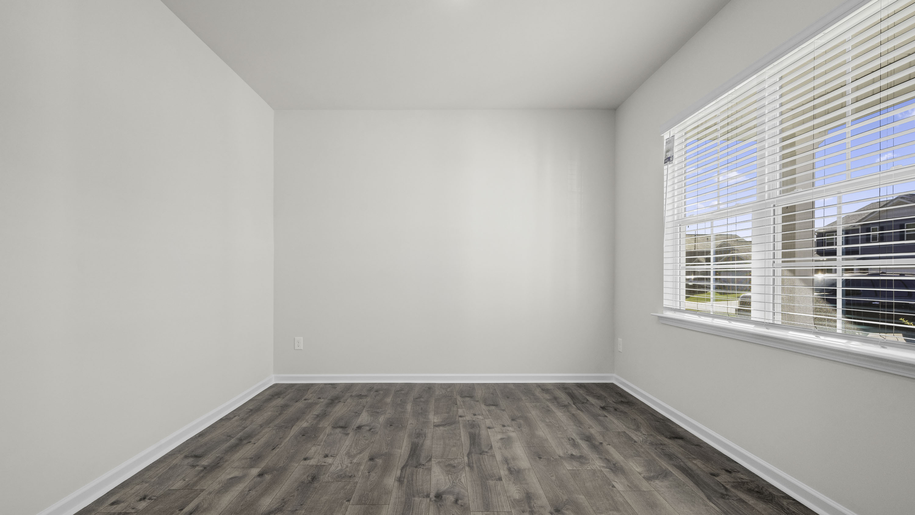 Neutral-toned interior space featuring wood-finish flooring and a multi-pane window with integrated horizontal blinds