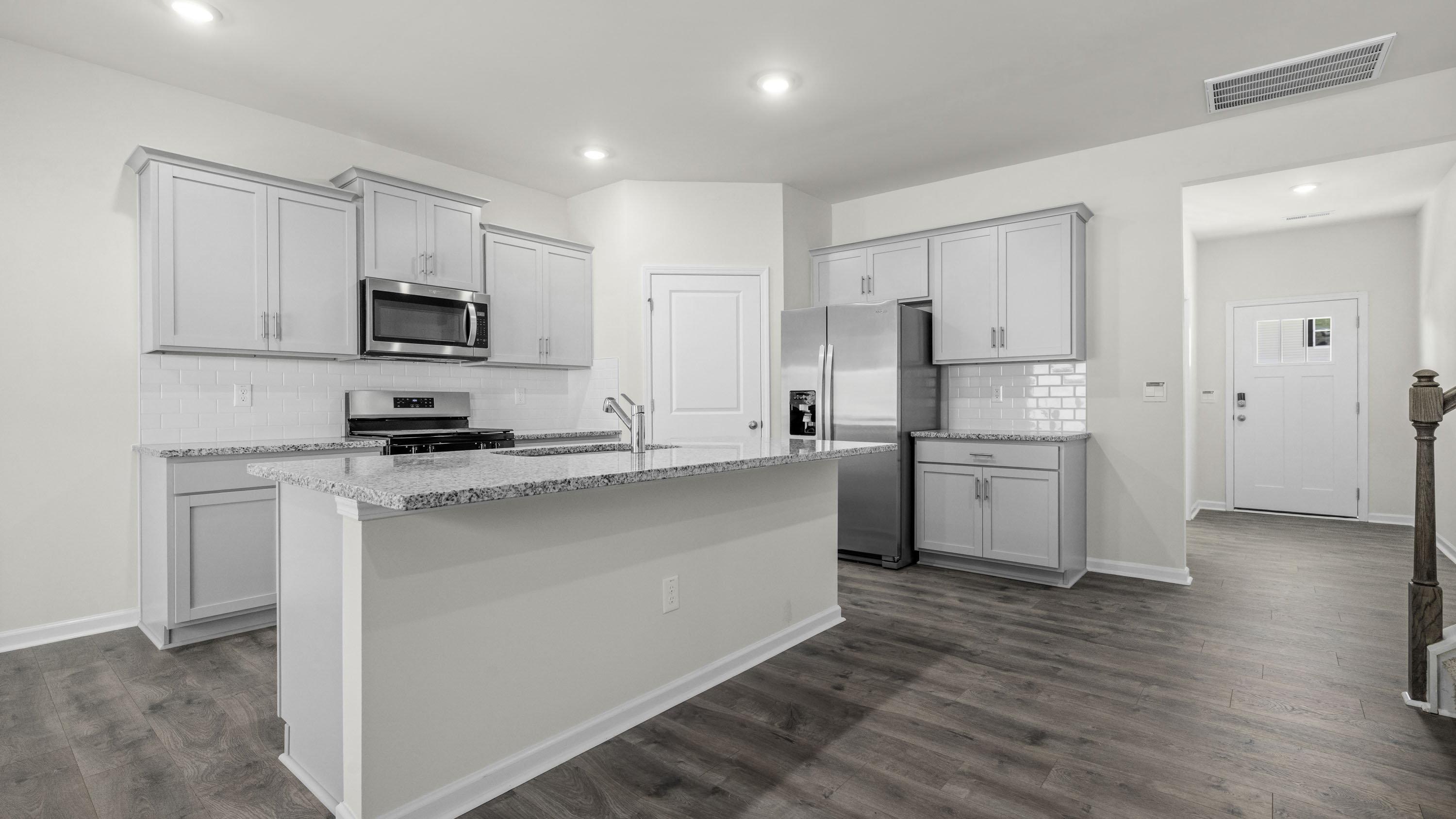 Kitchen featuring shaker-style cabinetry, stone countertops, stainless steel appliances, a central island, and wood-finish flooring