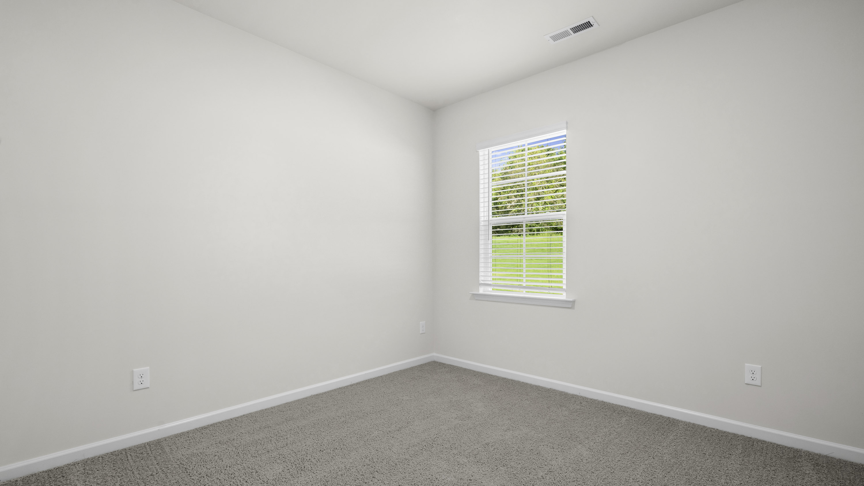 Neutral-toned interior featuring wall-to-wall carpeting, crisp white walls, and a single-hung window with integrated horizontal blinds