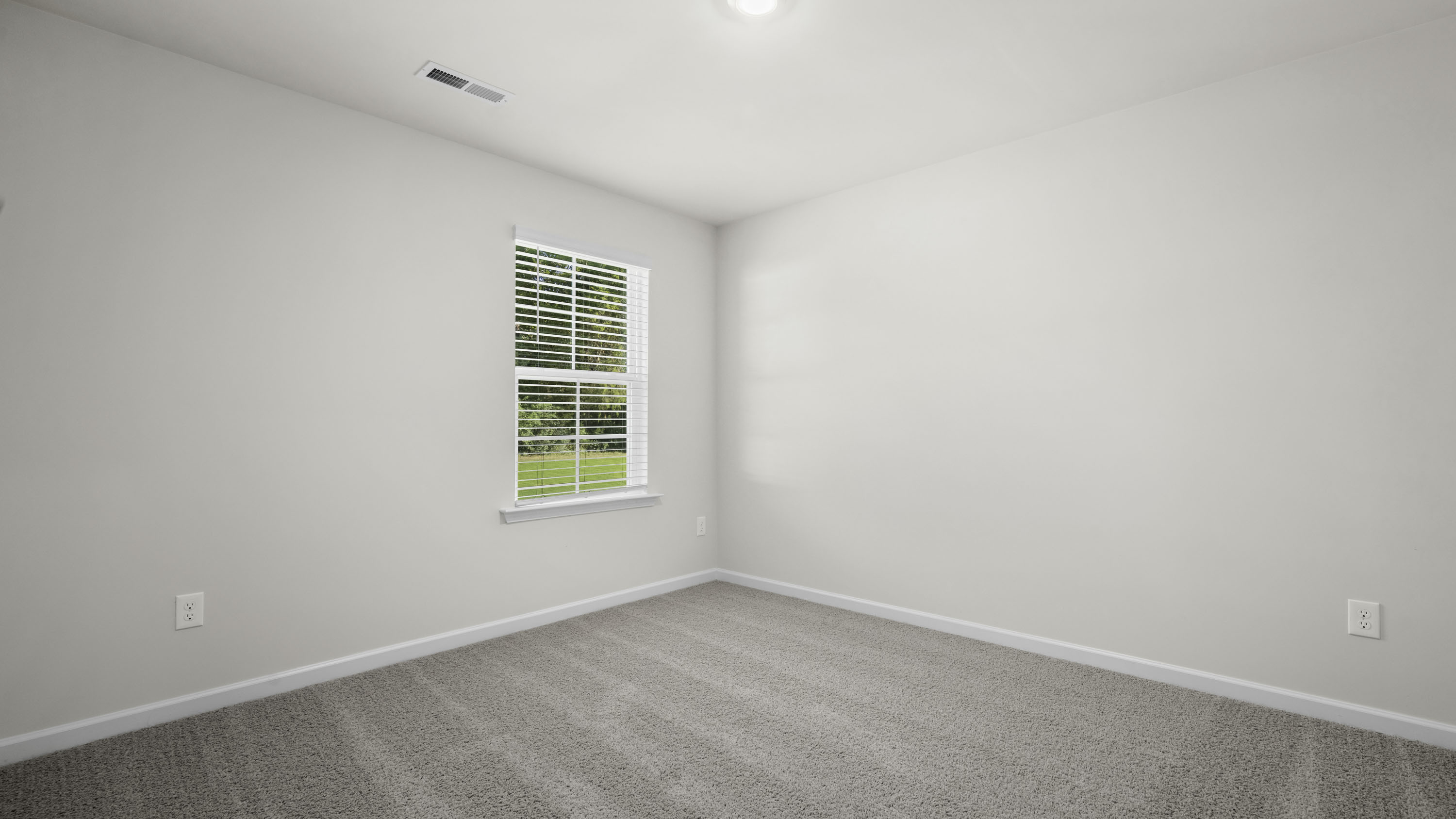 Neutral interior room featuring neutral-toned carpeting, light-colored walls, and a single-hung window with blinds