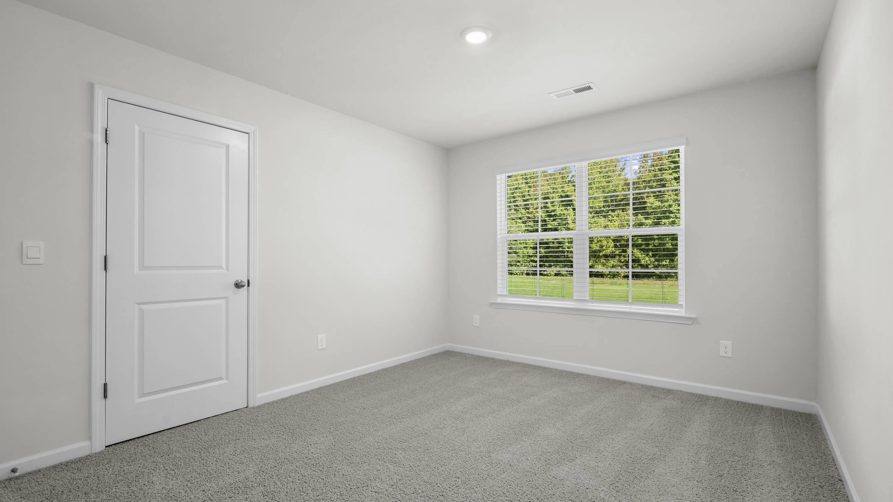 Neutral-toned interior room with high-pile wall-to-wall carpeting, recessed ceiling lighting, and a double-pane window