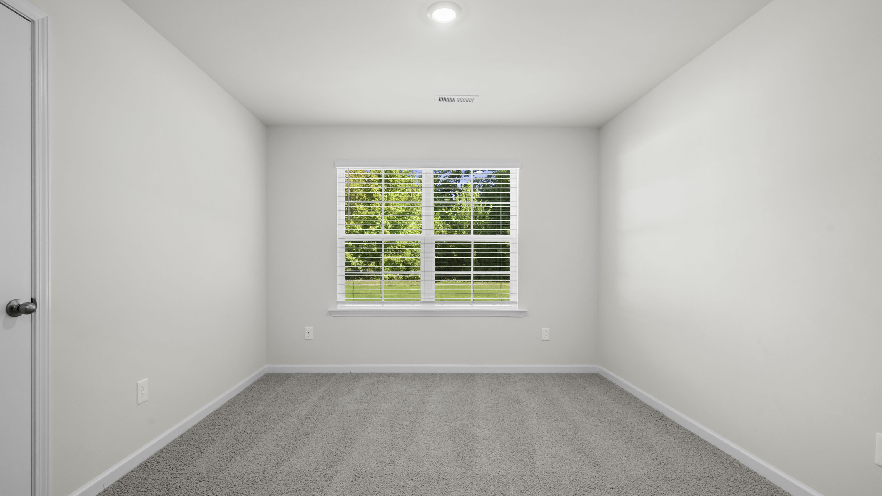 Neutral-toned interior space featuring light-colored wall paint, carpeted flooring, a multi-pane window, and recessed ceiling lighting