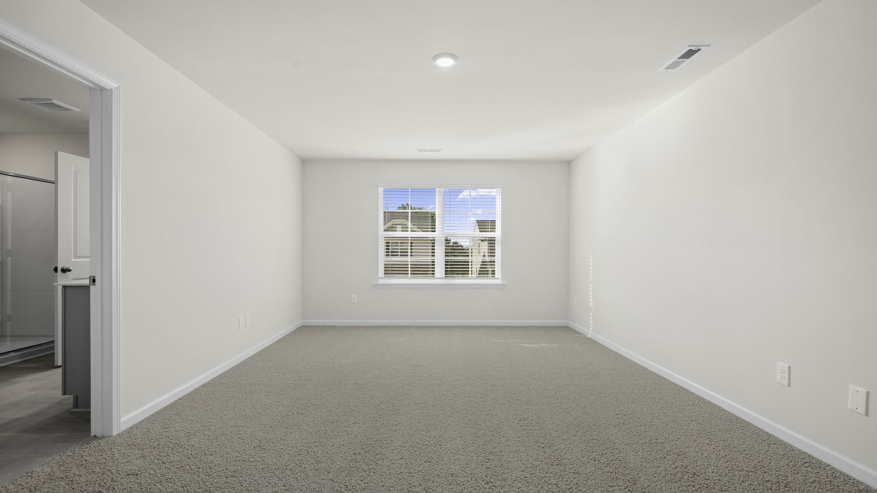 Interior space featuring neutral-toned carpeting, crisp white walls, a dual-pane window, and recessed ceiling lighting
