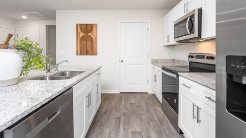 Kitchen with vinyl flooring, stainless steel appliances, an island and shaker style cabinets