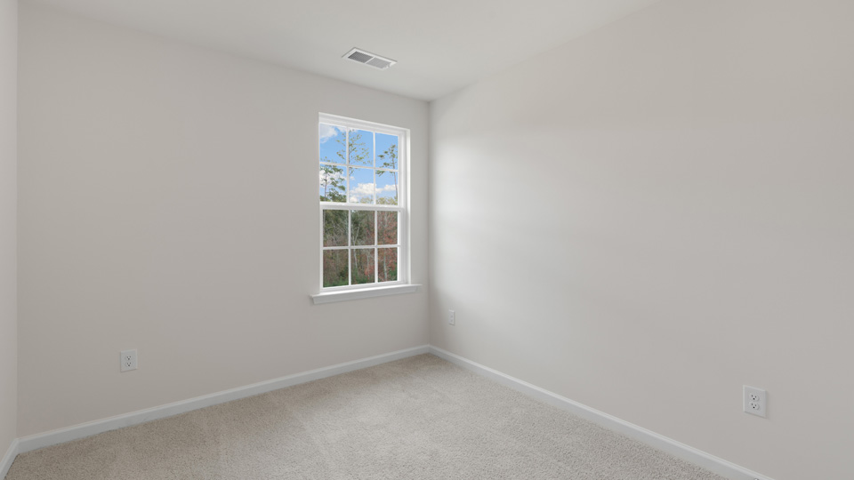 Neutral-toned interior space featuring light-colored wall paint and wall-to-wall carpeting, accented by a grid-pattern window
