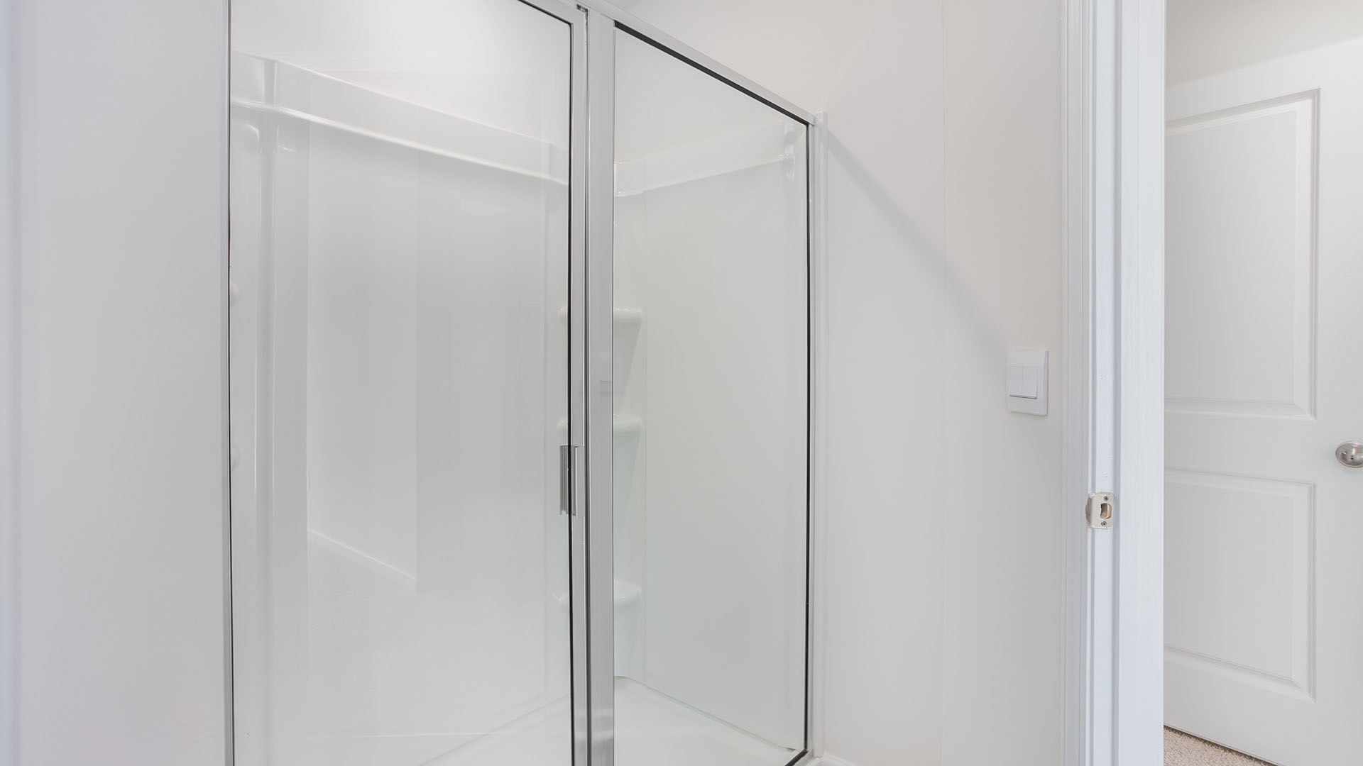 Shower enclosure with a glass door, chrome frame, and integrated shelving unit