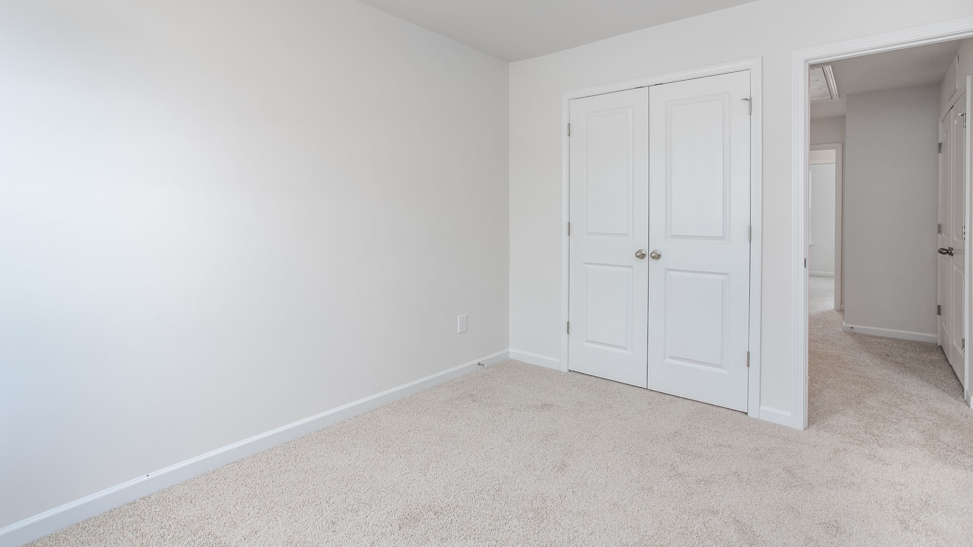 Interior space featuring neutral-toned carpeting and white dual-panel closet doors