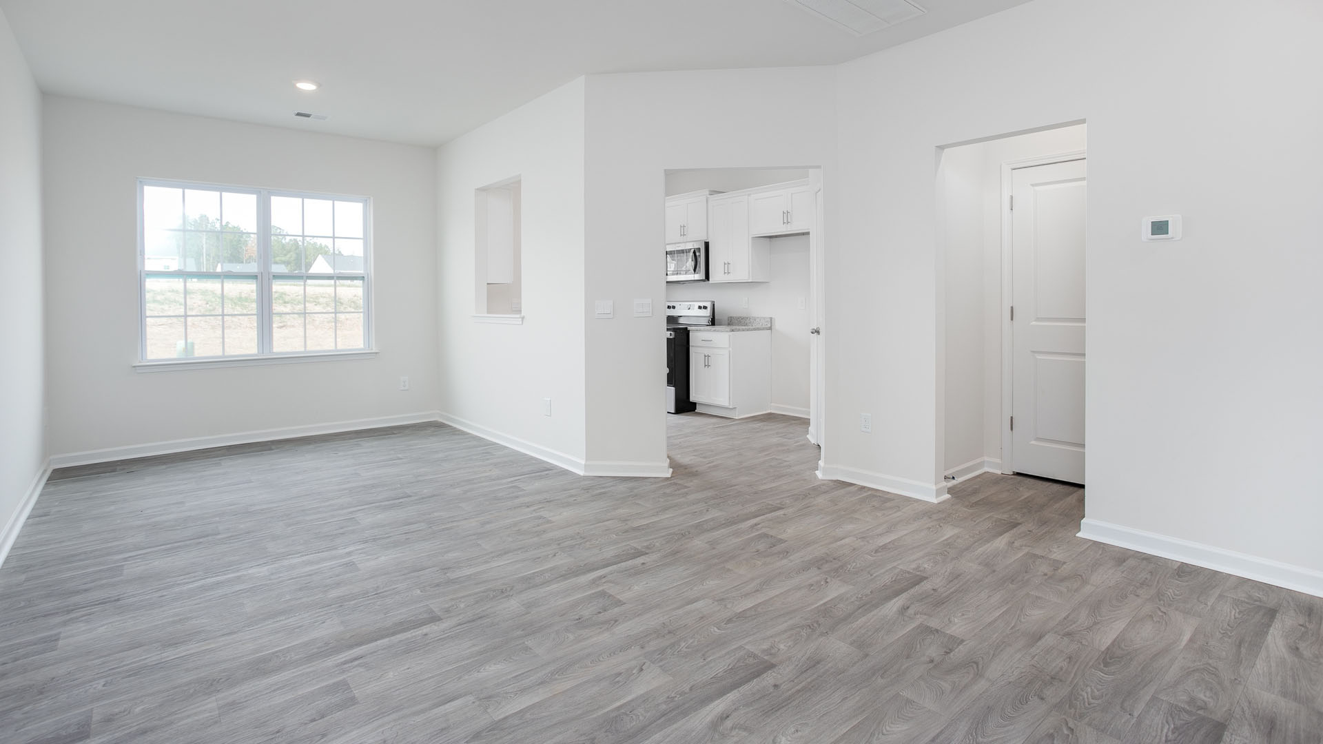 Neutral interior featuring wood-finish flooring, white walls, and a window with a grid pattern