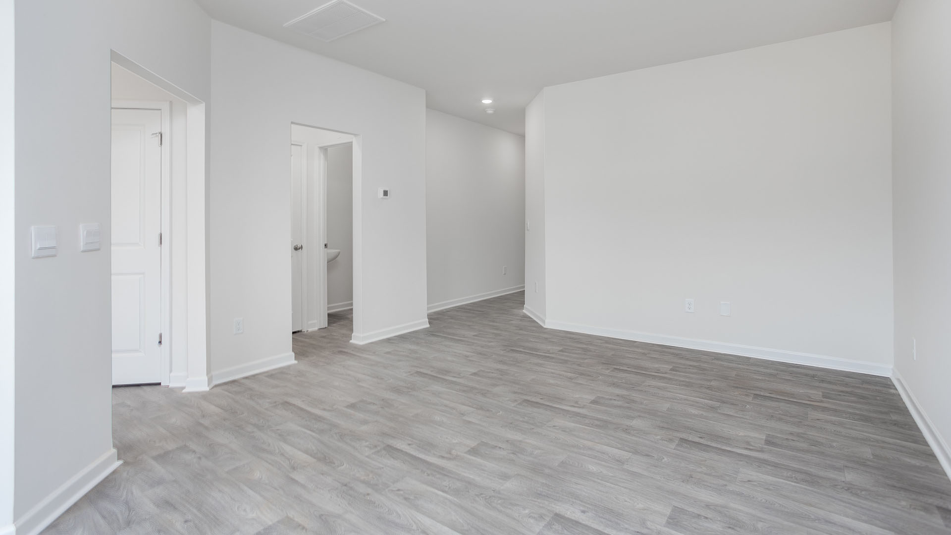 Interior space featuring wood-finish flooring, crisp white wall finishes, recessed ceiling lighting, and multiple interior doorways
