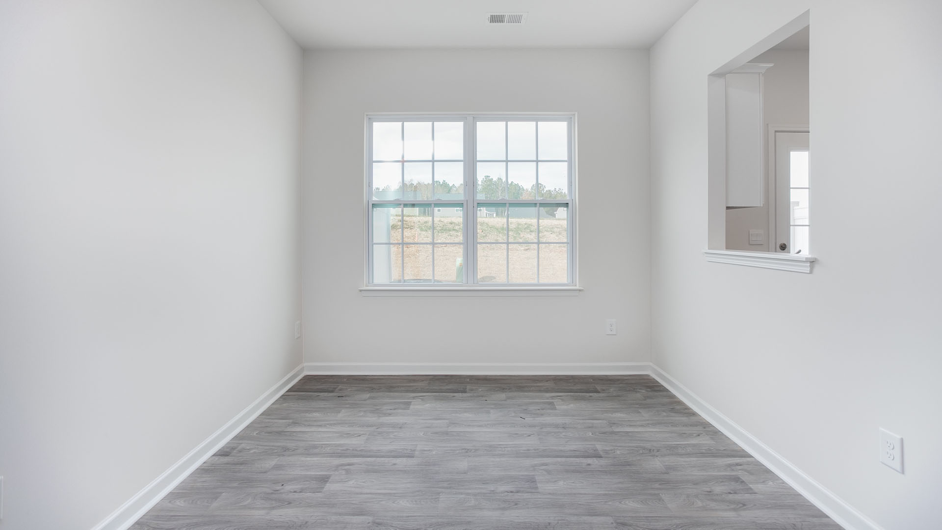 Neutral-toned interior featuring wood-finish flooring, a double-hung window with muntins, and a wall cutout