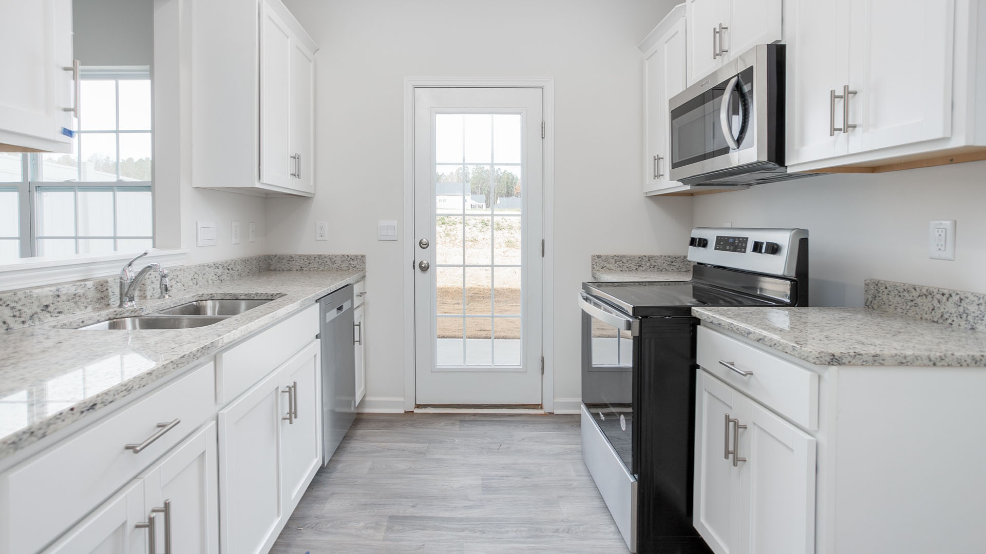 Kitchen featuring white cabinetry, stone-finish countertops, stainless steel appliances, wood-finish flooring, and a glass-paneled exterior door