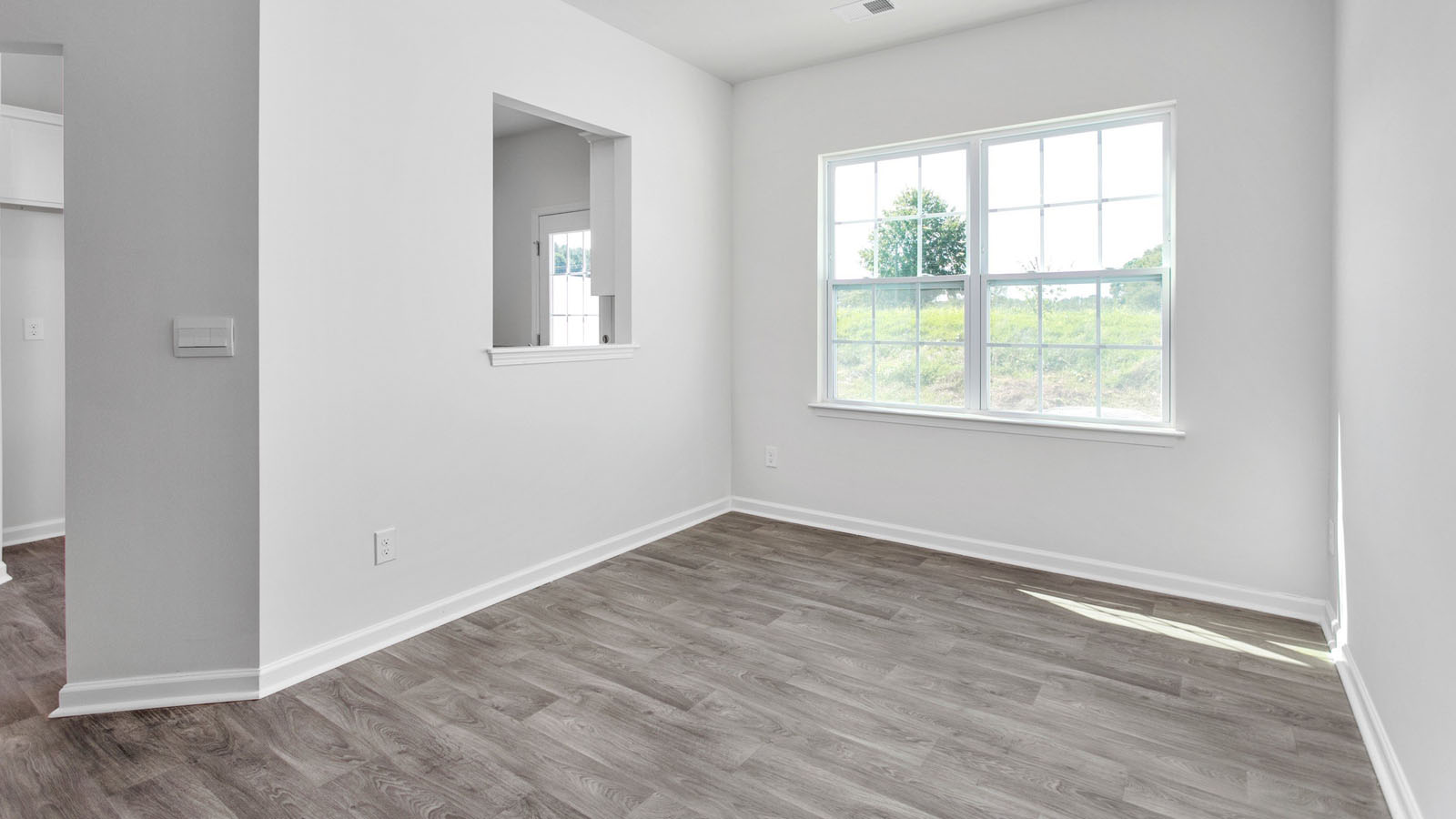 Neutral interior featuring wood-finish flooring, a double-hung window, and a pass-through wall opening