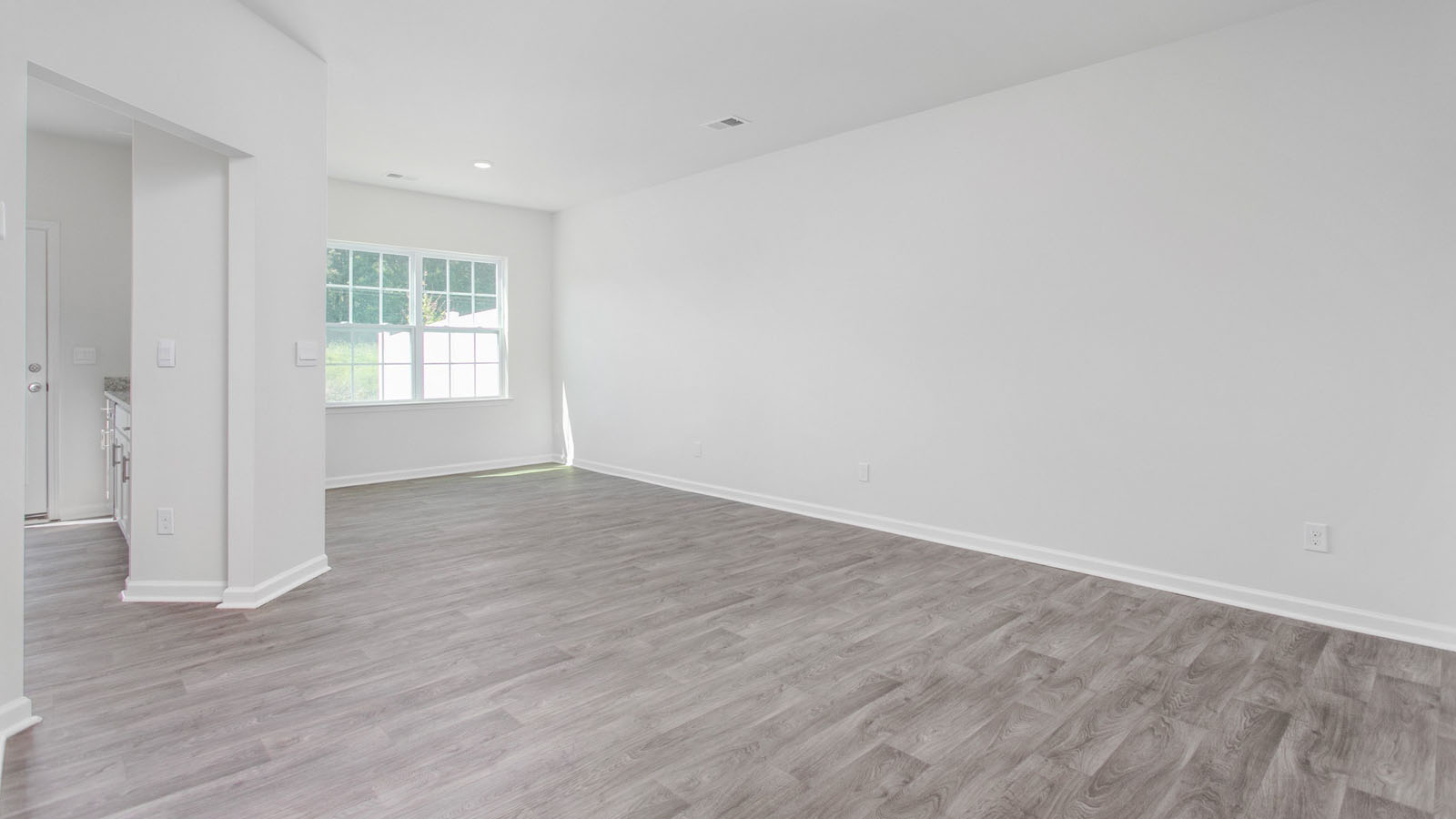 Open interior featuring wood-finish flooring, recessed lighting, and large windows with grid muntins
