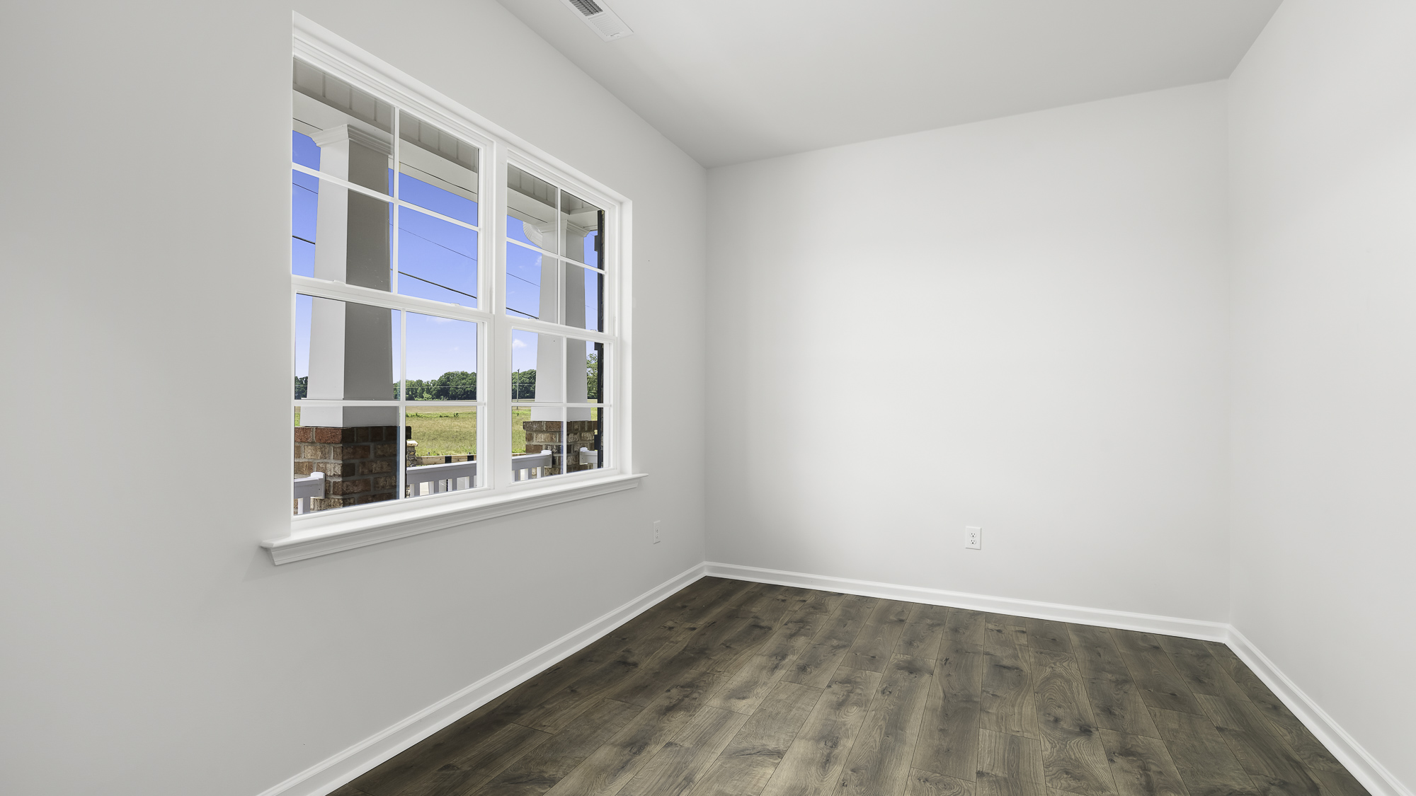 Room featuring neutral wall paint, wood-finish flooring, and a multi-pane window with a view of a porch