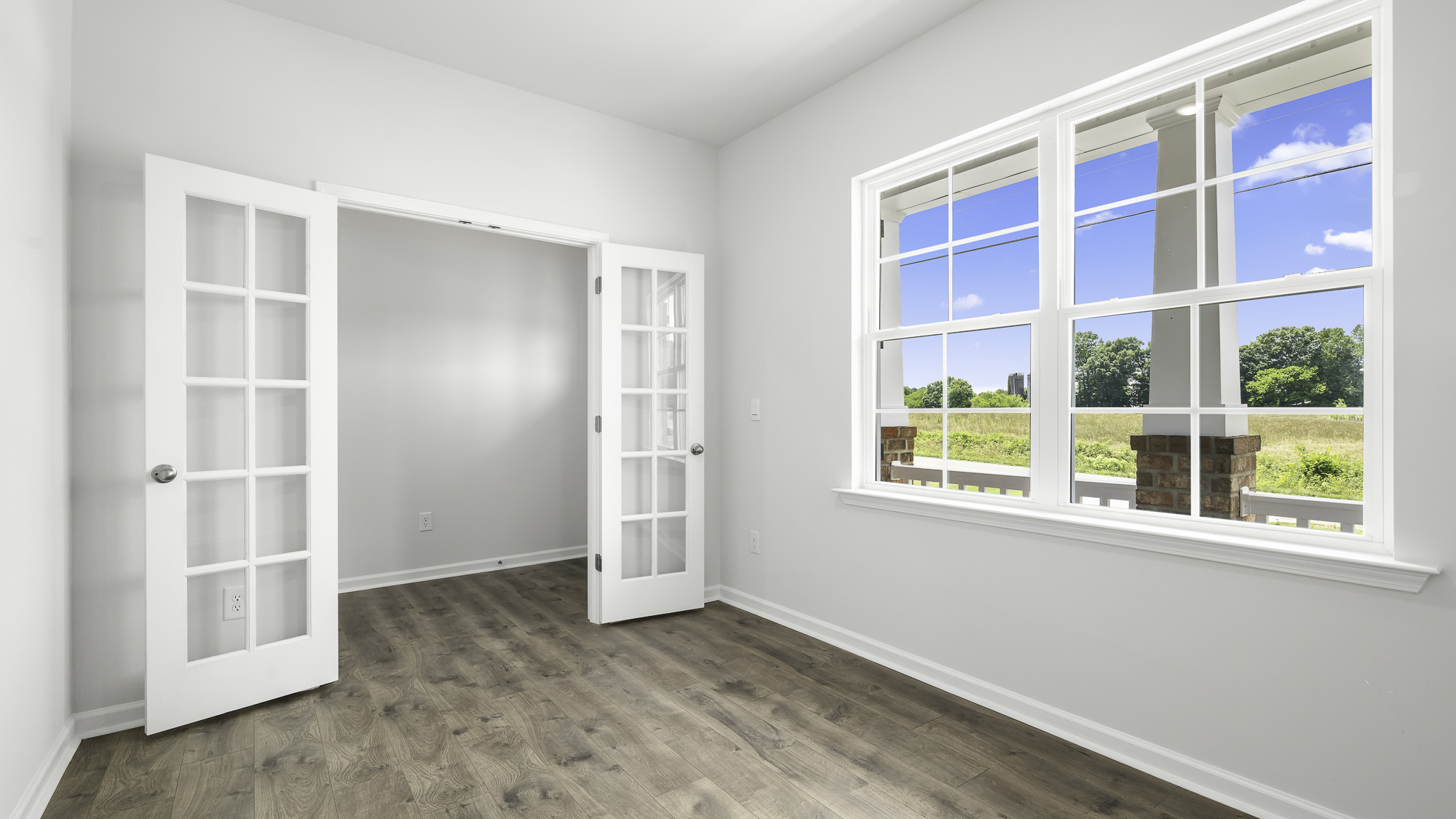 Interior space featuring wood-finish flooring, white walls, and glass-paned French doors