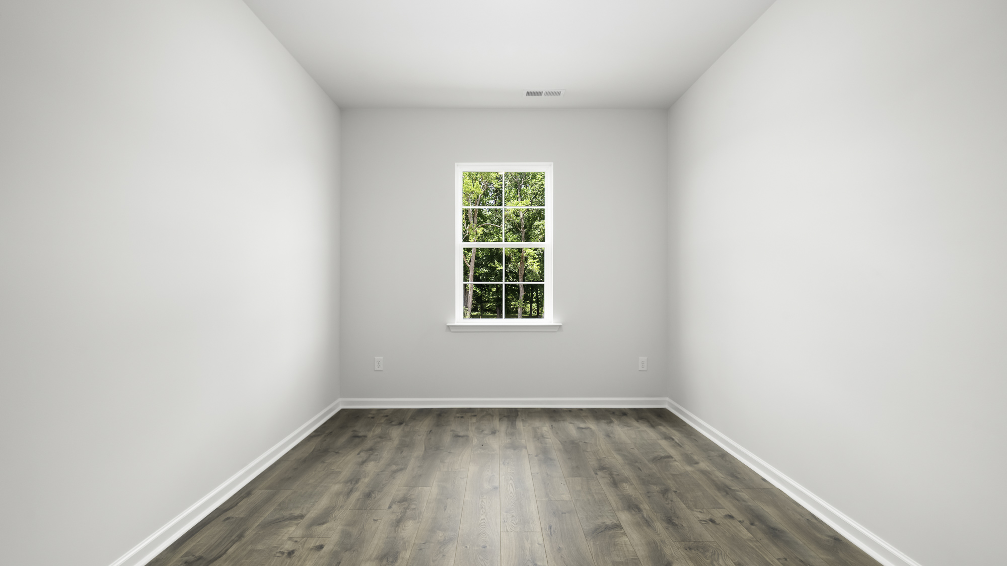 Neutral-toned interior space featuring wood-finish flooring and a single-pane window with exterior greenery