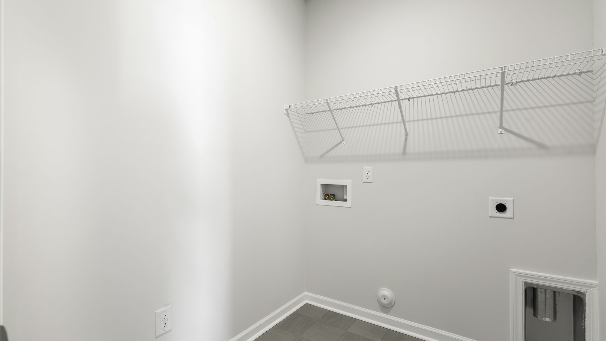 Utility space featuring neutral wall tones, vinyl tile flooring, and wall-mounted wire shelving