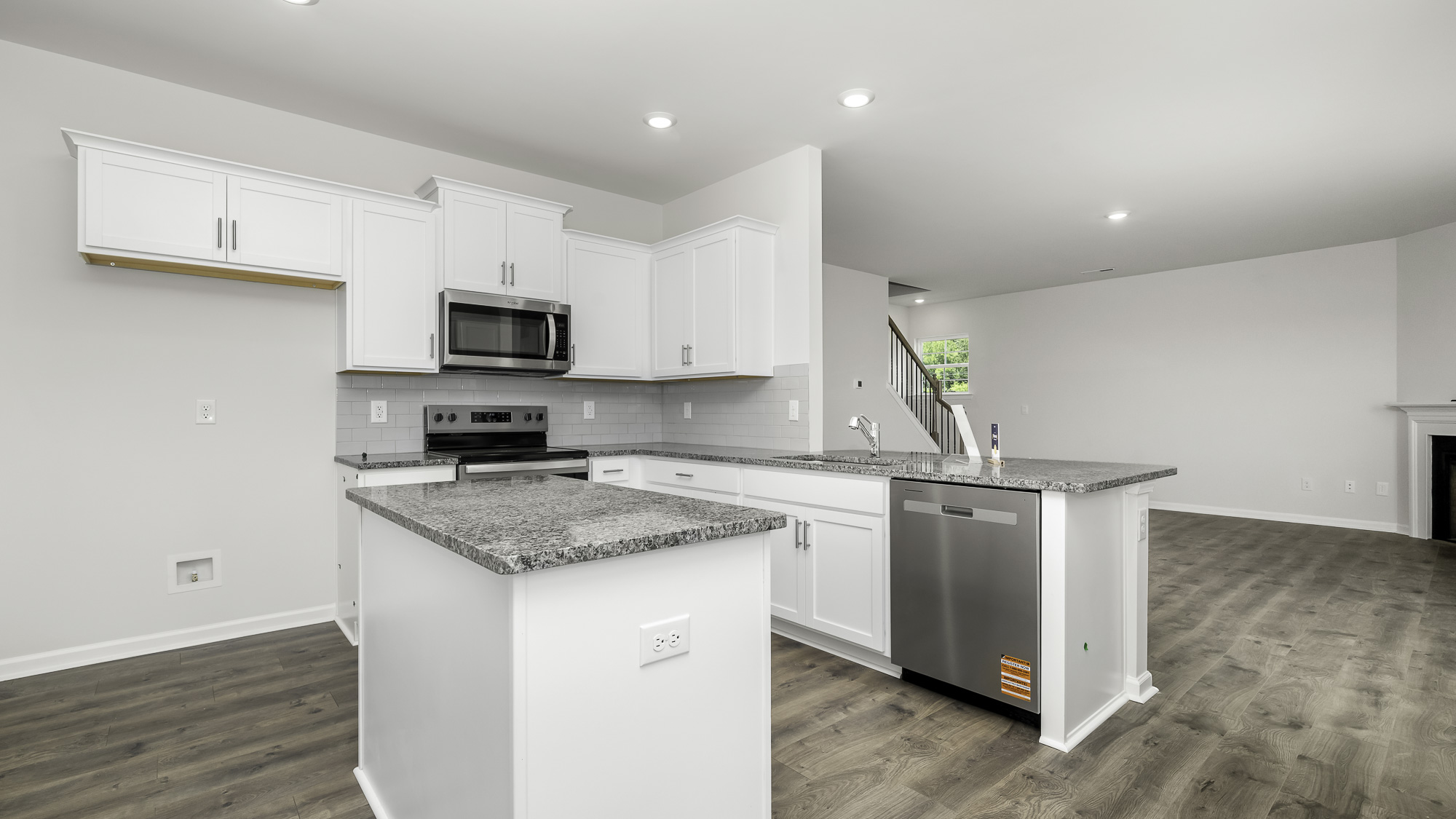 Kitchen featuring white shaker-style cabinetry, stone-finish countertops, stainless steel appliances, a center island, and wood-finish flooring
