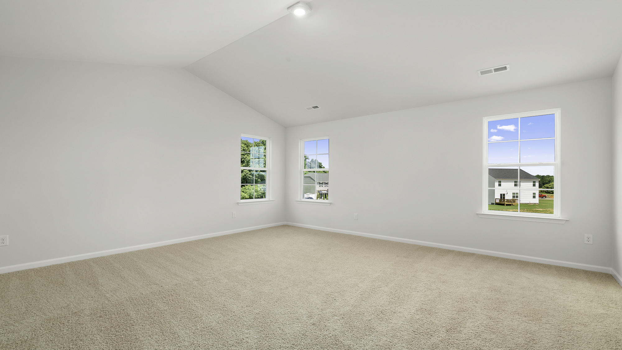 Vaulted ceiling featuring neutral wall-to-wall carpeting and three multi-pane windows