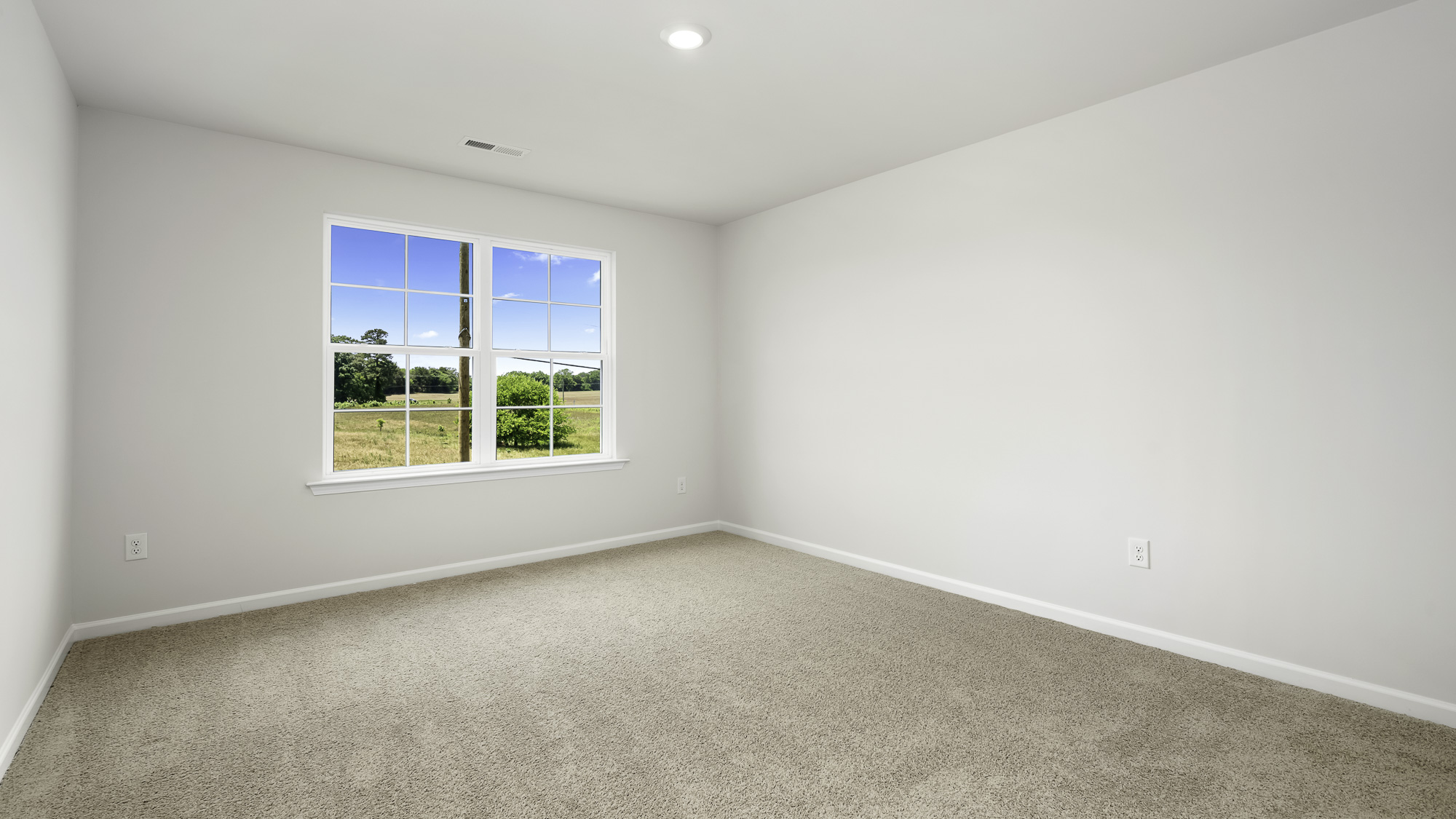 Neutral-toned room featuring plush wall-to-wall carpeting, recessed ceiling lighting, and a multi-pane window with exterior landscape imagery