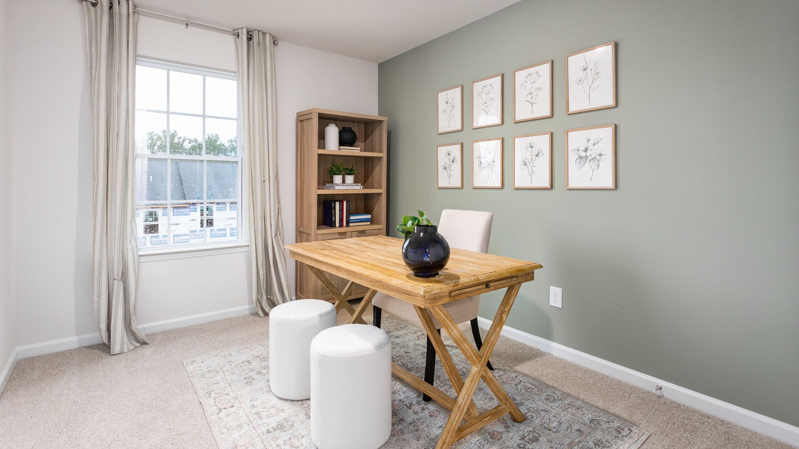 Neutral-toned interior space featuring a multi-pane window, wall-to-wall carpeting, and a sage green accent wall
