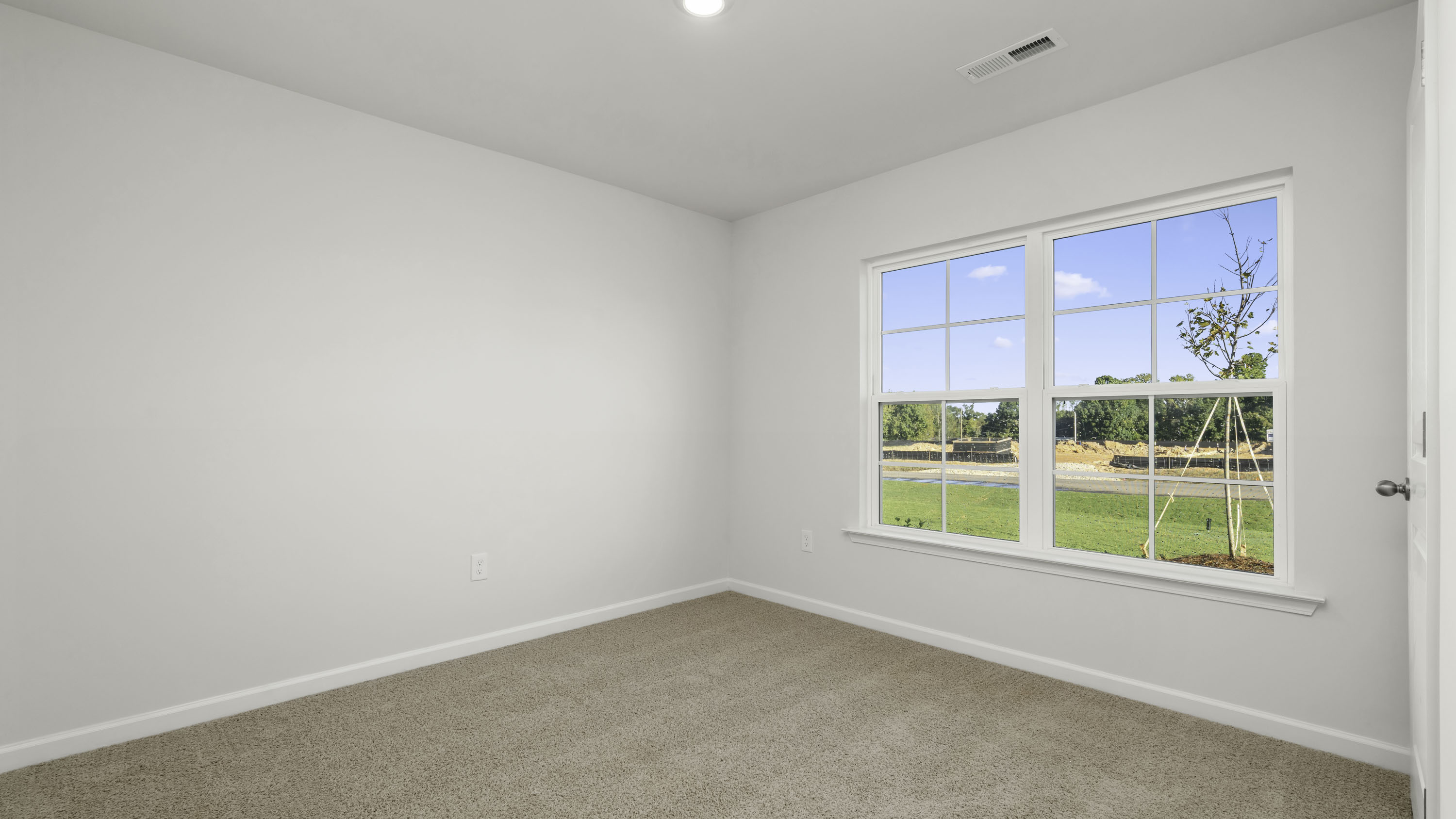 Neutral-toned interior featuring wall-to-wall carpeting, recessed ceiling lighting, and a multi-pane grid window