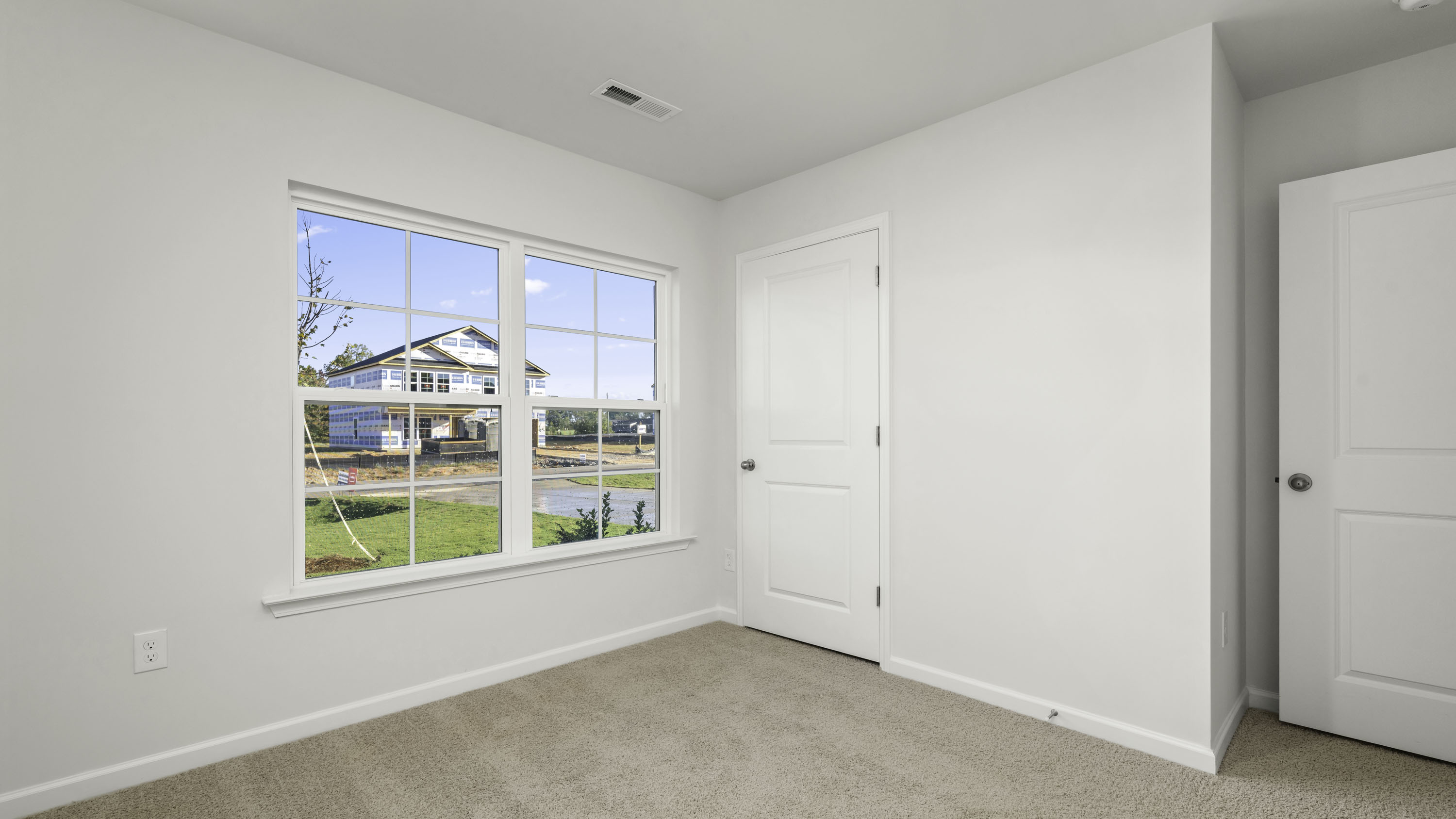 Neutral wall paint, multi-pane window with white trim, wall-to-wall carpet, and two-panel interior doors