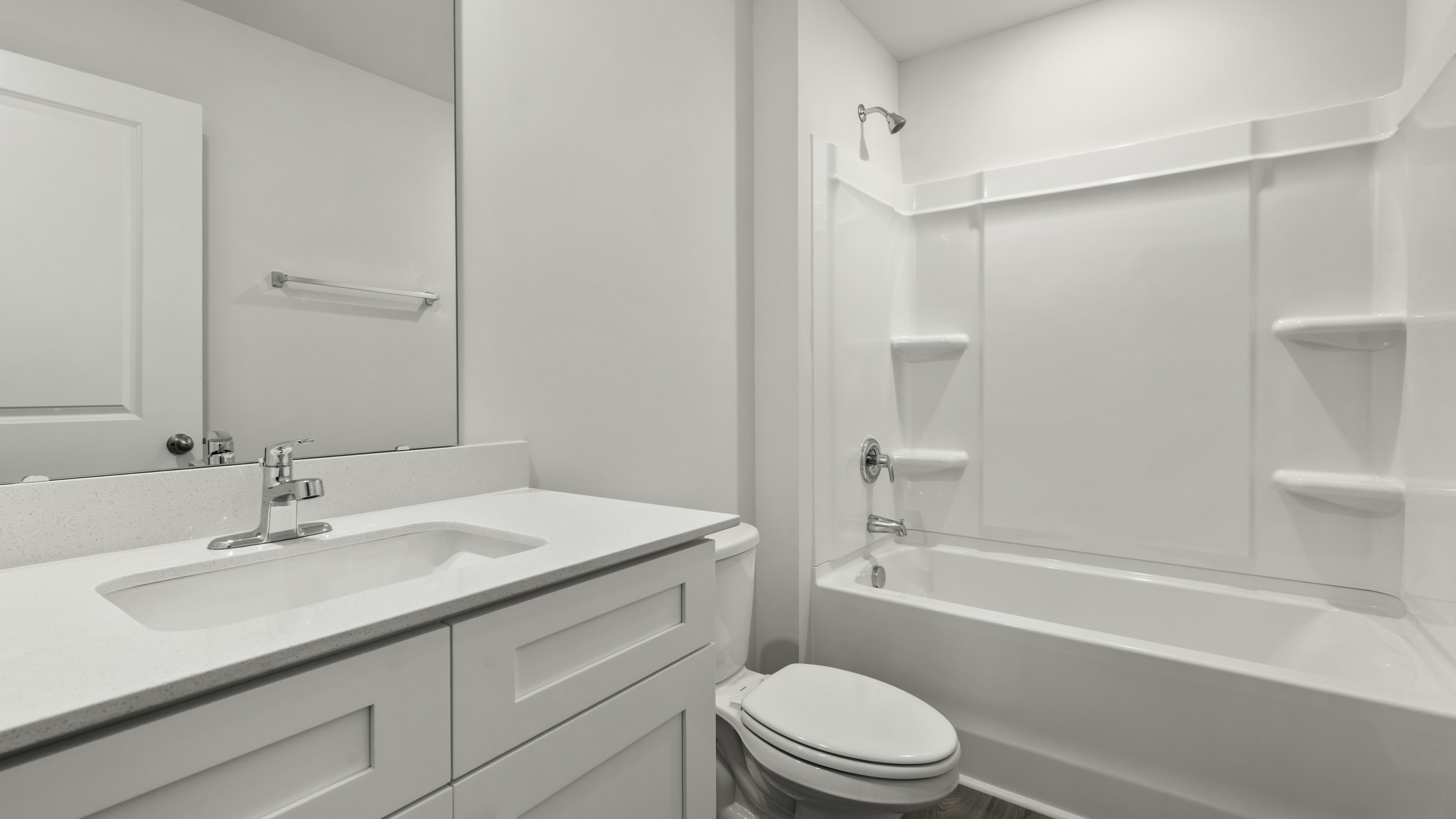 Bathroom featuring a vanity with a white countertop and integrated sink, a full-height wall mirror, and a tub-shower combination with built-in shelving